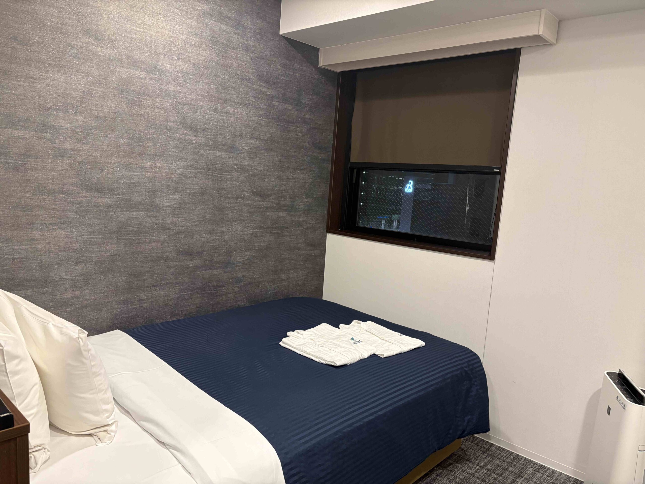 Hotel LiveMax的雙人床對著一個小窗戶，早上陽光灑落很舒服