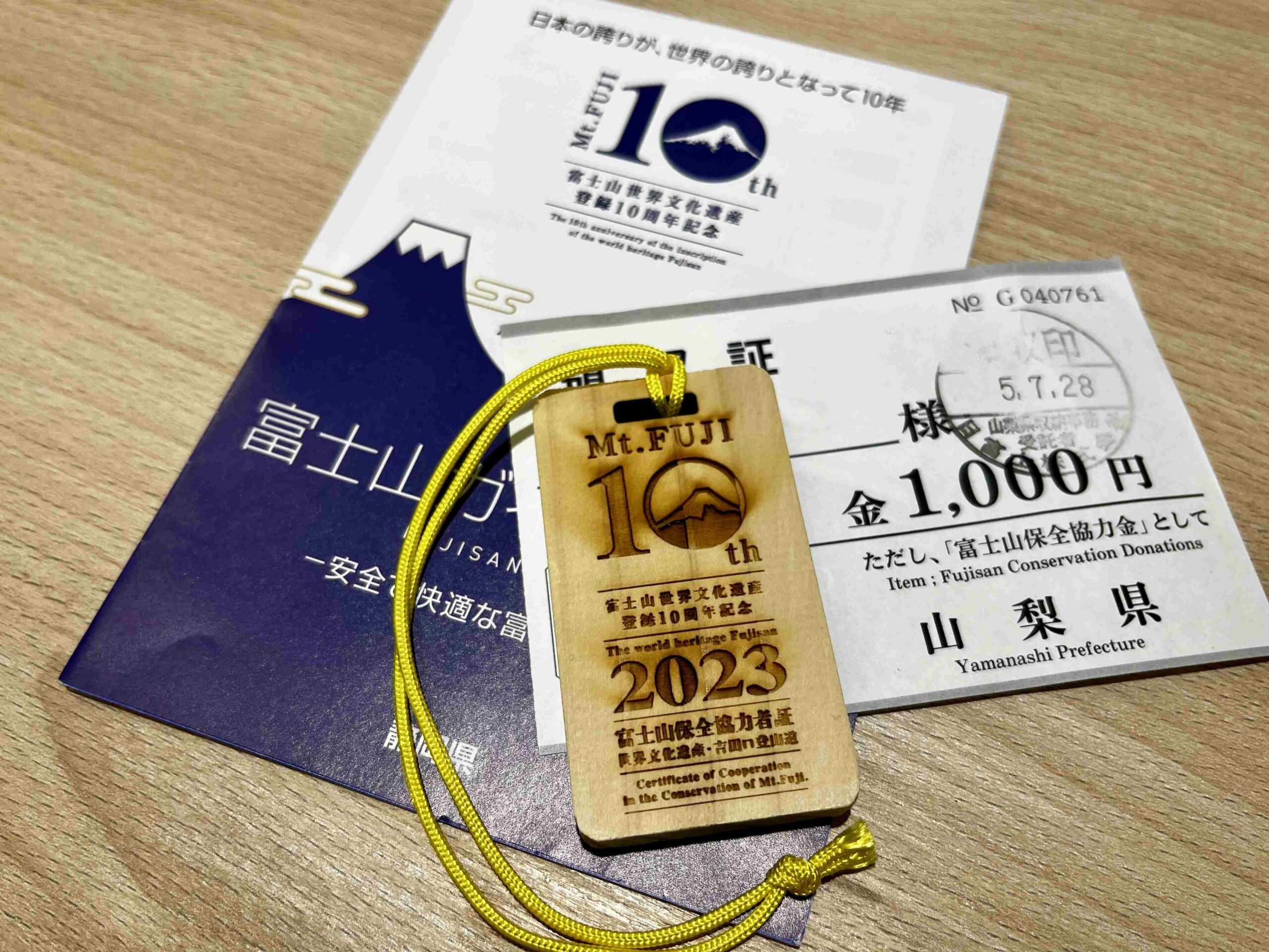 2023爬富士山全記錄(中):入住最高山屋8.5合目的御來光館|日本旅遊・山景 7 富士山登陸世界遺產10週年紀念版「富士山保全協力者證」木牌,以及富士山導覽小手冊、捐款收據。
